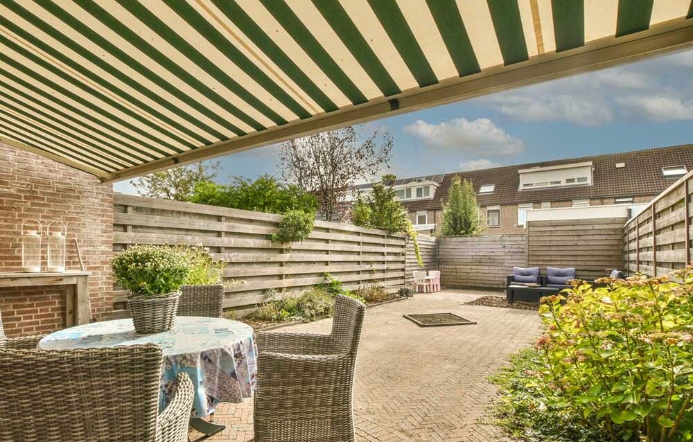 WhatsApp Image 2026-03-18 at 11.17.45 (1) Manual retractable outdoor blinds extended over a patio area, providing shade and enhancing a comfortable outdoor living space.