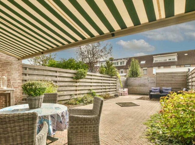 WhatsApp Image 2026-03-18 at 11.17.45 (1) Manual retractable outdoor blinds extended over a patio area, providing shade and enhancing a comfortable outdoor living space.