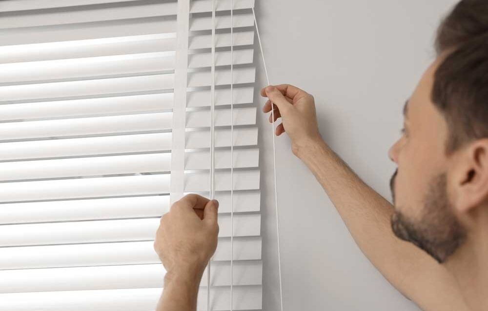 WhatsApp Image 2026-05-14 at 3.32.25 PM Manual outdoor blinds being adjusted by homeowner for light and privacy control in a modern home interior